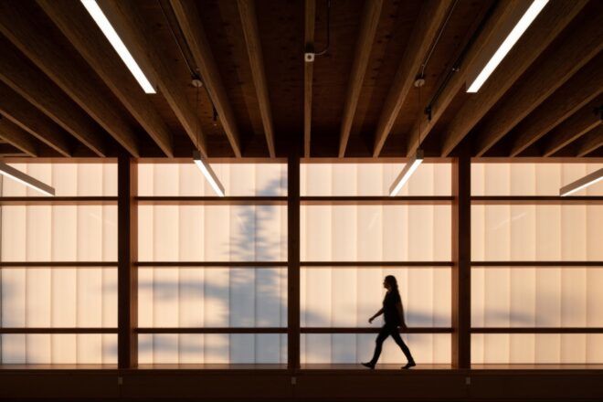 silhouette of person walking through room with wood-framed glass walls