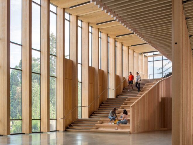 people sitting on large wood staircase near wall of glass