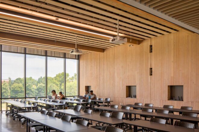 long tables in room with wood walls and ceilings and one end wall of glass