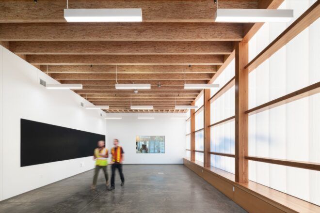 people walking through hallway with white walls and wood ceilings