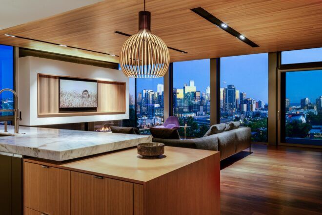 A wood counter with a hanging lamp overhead. In the background, floor-to-ceiling walls showing views of the city.