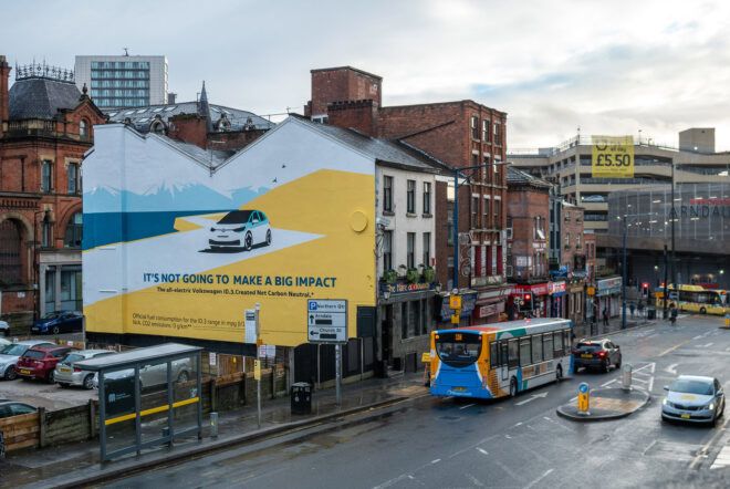 A streetscape in London with a large painted VW ad on the side of a building to the left.