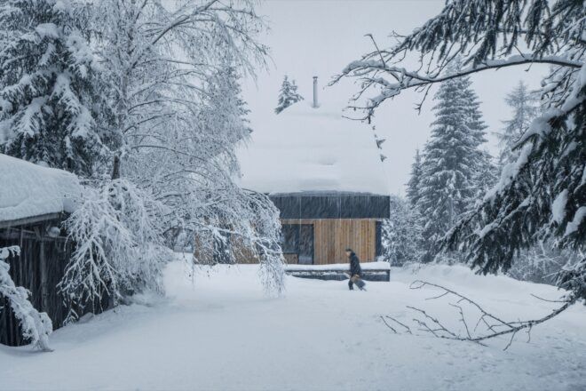 person walking in front of snow-covered cabin