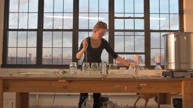 person dropping liquid into jars in a lab setting