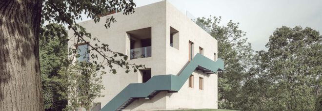 large teal staircase wrapping around exterior of cube stone home