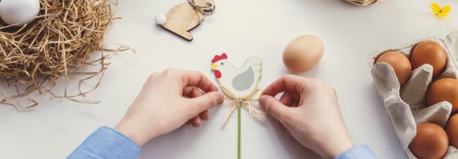 person making wooden chicken and rabbit decorations with eggs in cartons off to the side