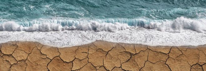 Waves rushing onto cracked, dry land.