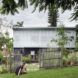 A person sitting in the grass just outside a gate surrounding the home.