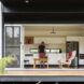 Open sliding glass doors look into a sitting room where two family members lounge.