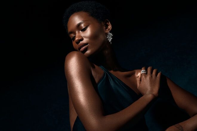 person wearing diamond ring and diamond earrings