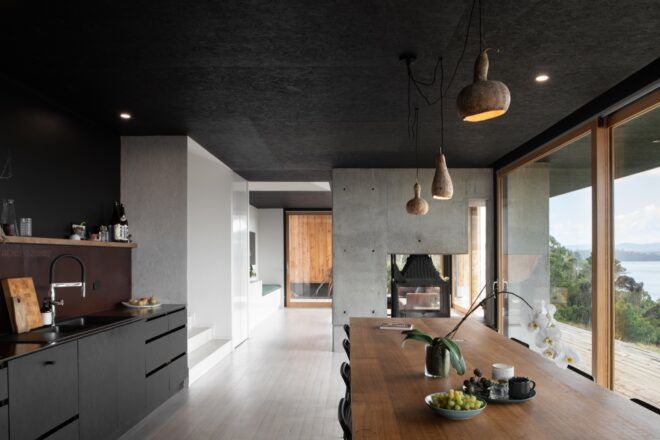 kitchen with black cabinets next to long, dark wood dining table
