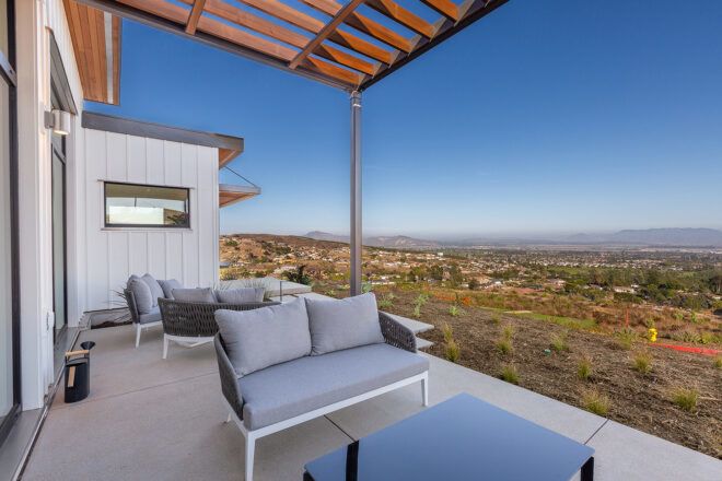 gray patio seat and black table on outdoor patio overlooking desert landscape