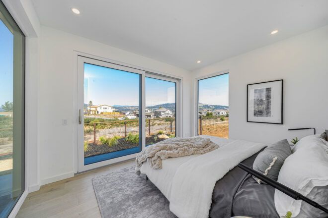 large bed facing sliding glass doors with mountain views