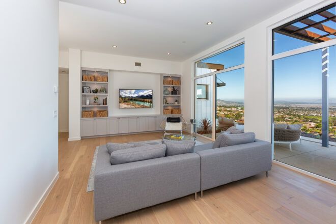 gray sofa facing mounted TV near a wall of glass