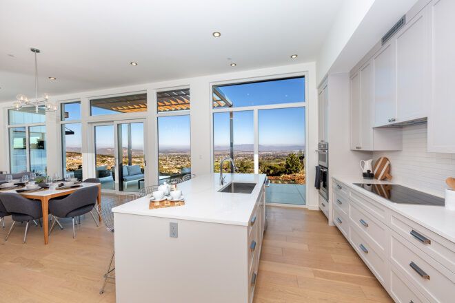 white kitchen with large island near wall of glass
