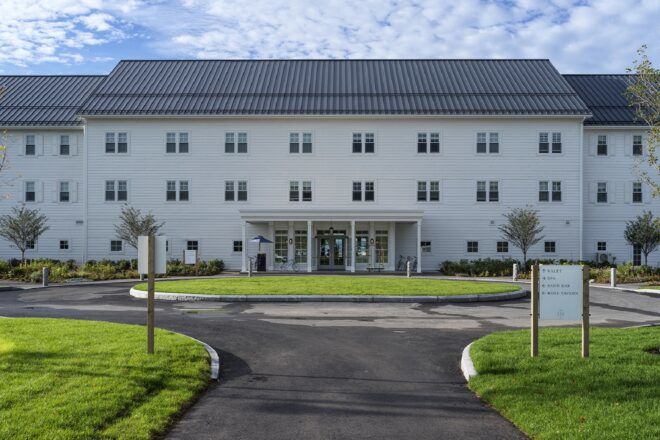 A three-story hotel with a green path leading up to it.