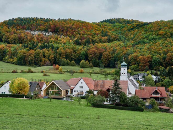A rolling green landscape with traditional village buildings nestled into the land.