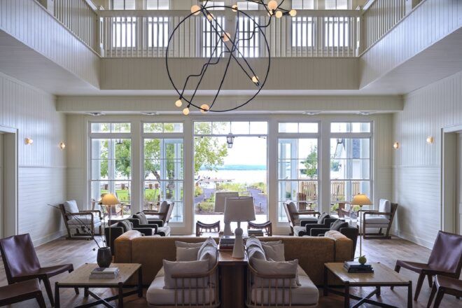A hotel lobby with white accents, sitting room furniture and a circular, avant-garde light fixture overhead.