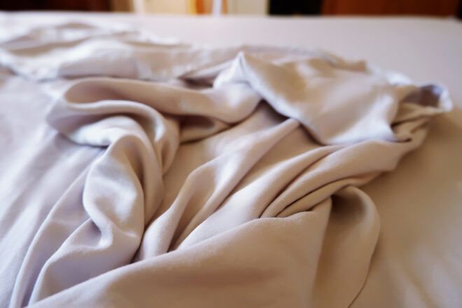 gray sheets on an unmade bed