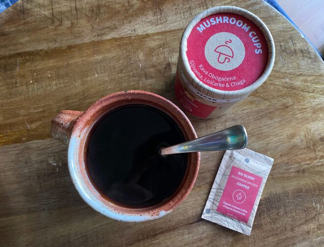 container of Mushroom Cups brand coffee next to cup of hot coffee