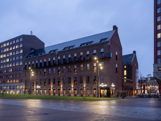 angled view of old brick building lit by flood lights at dusk