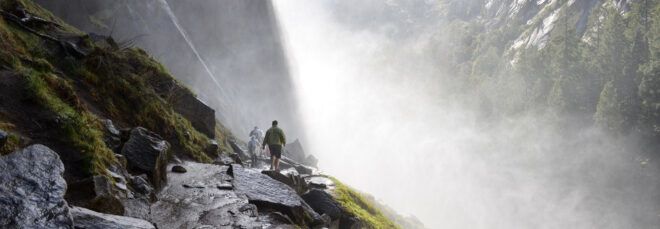 people hiking on rocky cliff in Yosemite National Park