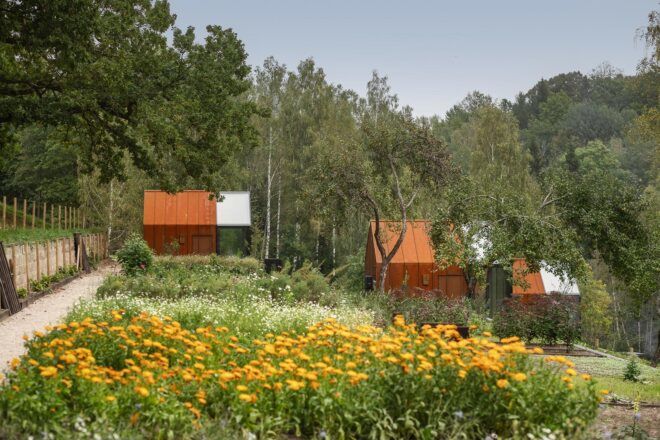 weathered steel and glass cabins in a meadow