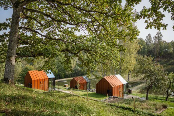 series of weathered steel and glass tiny cabins on a hill