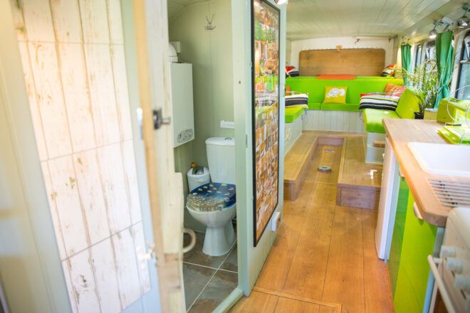 A bathroom off the hallway inside the bus with green accents and wood floors.