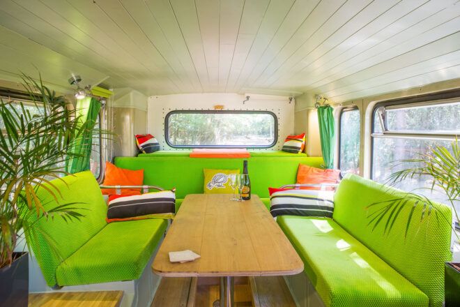 A table inside the bus with green accents and wood floors.