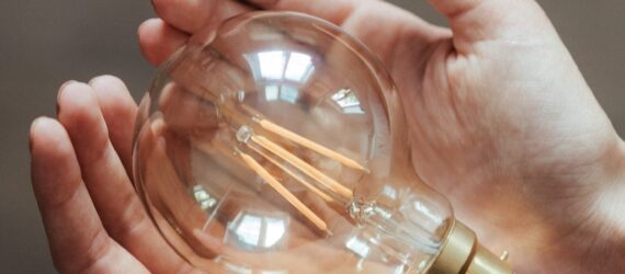Two hands holding a light bulb.