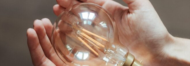 Two hands holding a light bulb.