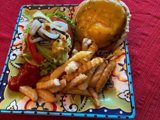 vegan burger with lettuce, tomato, onion and fries on plate