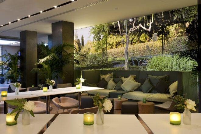 A green hotel lobby with chairs, tables and sofas.