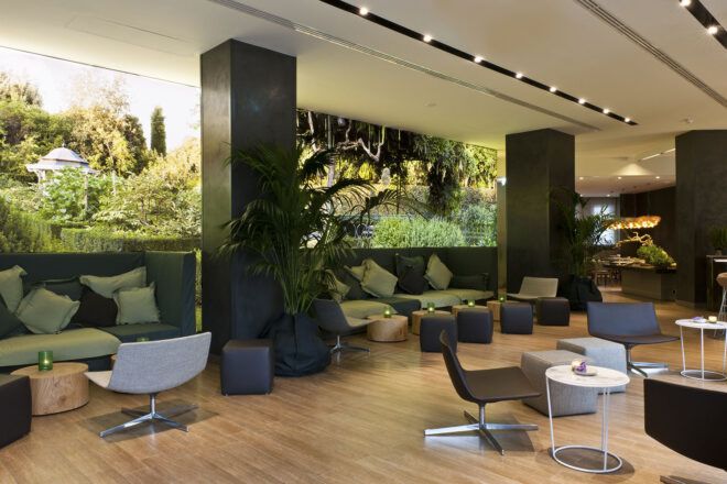 A green hotel lobby with chairs, tables and sofas.
