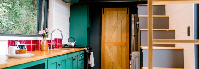 tiny home kitchen with butcher block counters and dark green cabinets