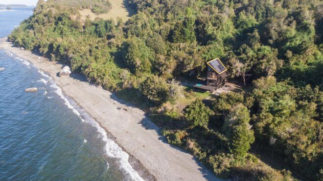 aerial view of cabin in forest just steps from a beach