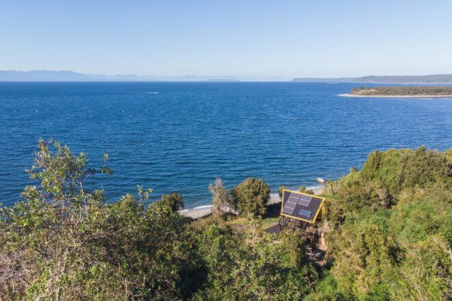 solar-powered dark wood cabin facing the ocean