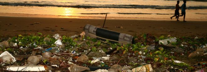 A beach at sunset, the coast littered with trash.