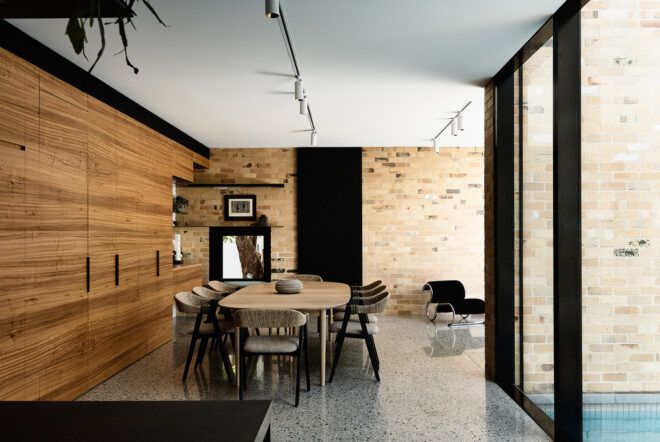 A dining room with a dining table and chairs, all of which follow a wood and black color scheme.