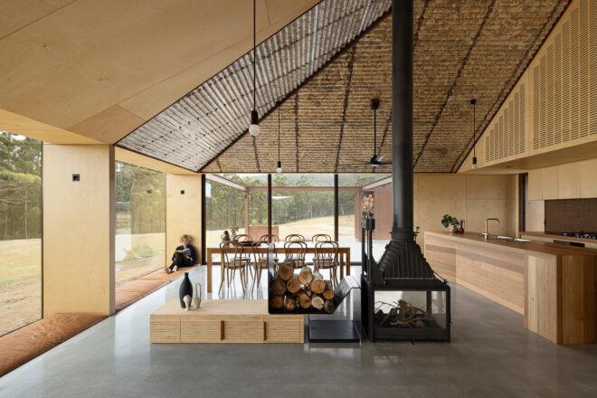 wood-lined living area with dining table near walls of glass