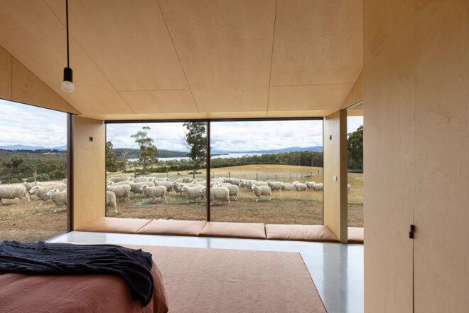 red bed facing wall of glass with farm views