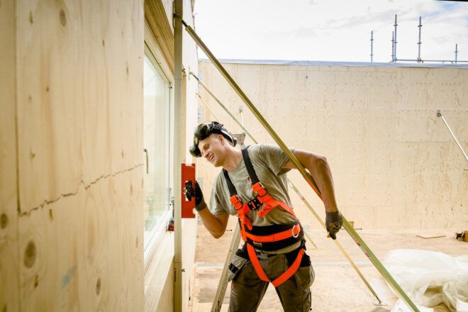 A person in a construction uniform working on a wood wall.