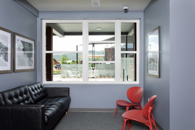black leather sofa and red chairs near blue wall with large window