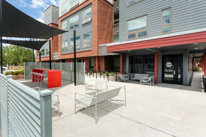 white bench on patio near gray and red building