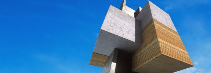 A cube-like structure of wood and concrete against a blue sky background.
