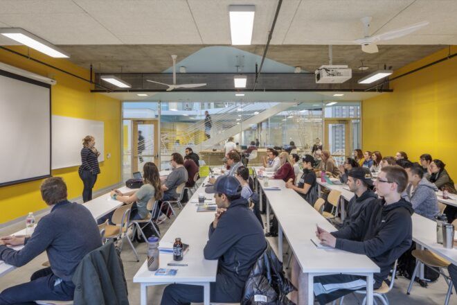 college students sitting at long white desks in yellow room