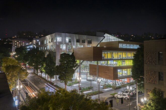 cantilevered wood college building lit from within at night
