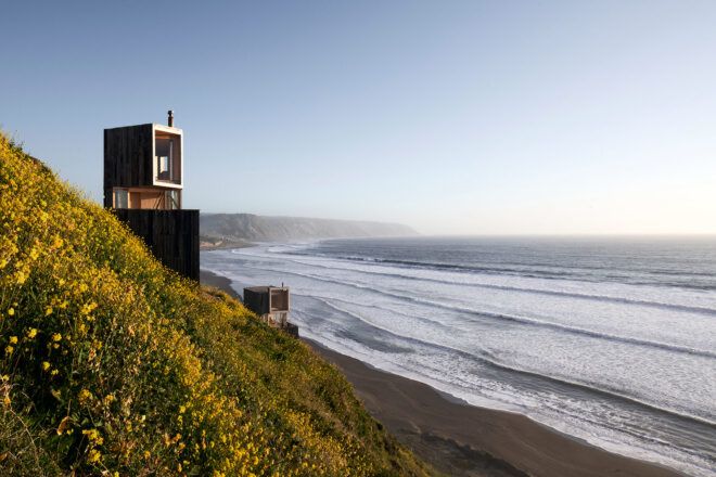 two wood cabins on hillside by ocean