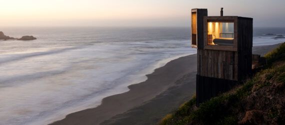 light and dark wood cabin overlooking the ocean at dusk